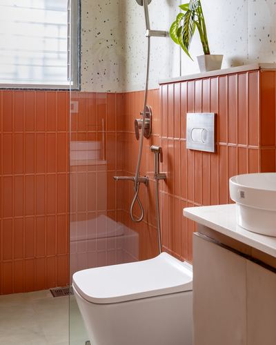 Bathroom with ribbed terracotta tile, terrazzo wall, glass shower partition, and wall-hung toilet