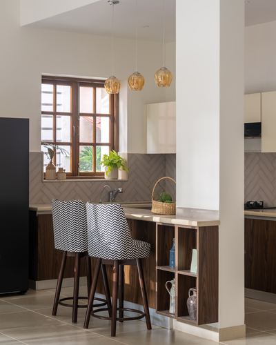 Kitchen counter with chevron-patterned stools, amber pendant lights, and a wooden window with tiled backsplash