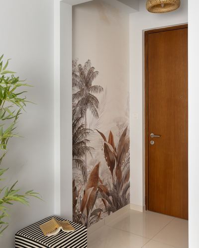 Foyer with tropical wallpaper niche, wooden door, striped ottoman and plant
