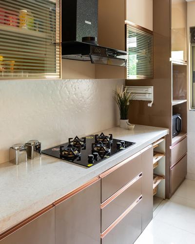 Galley kitchen with bronze cabinetry, black gas hob, chimney hood and textured stone backsplash