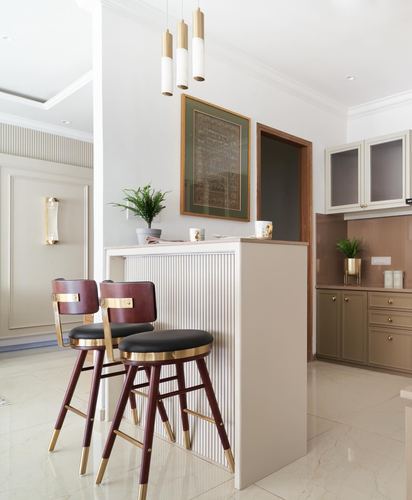 Kitchen counter with fluted paneling, brass pendant lights, and maroon leather bar stools