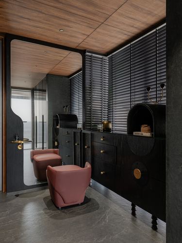 Dark wood dressing area with arched mirror, black cabinetry, brass hardware, and two mauve leather chairs.