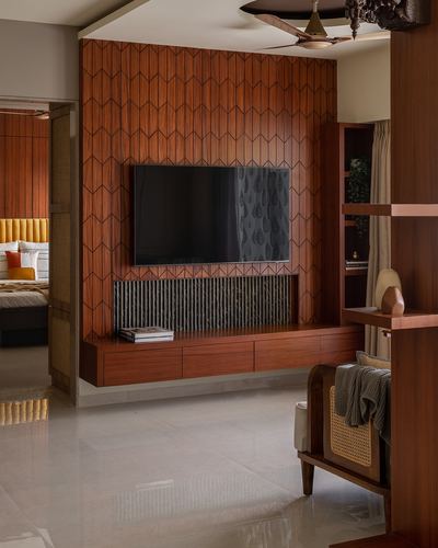 Living room with chevron wood-clad tv wall, floating console, and glimpse into bedroom