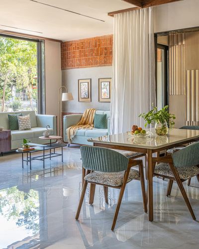 Open living-dining space with terracotta tile accent wall, sage sofas, and a wood dining table with patterned chairs