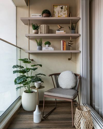 Balcony reading nook with cane chair, brass-framed shelves, and potted plants