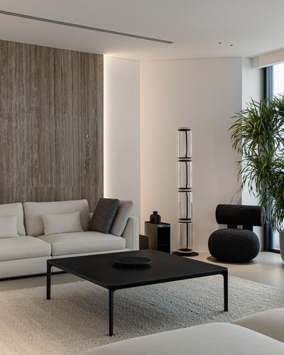 Minimalist living room with stone accent wall, black coffee table, white sofa and sculptural floor lamp