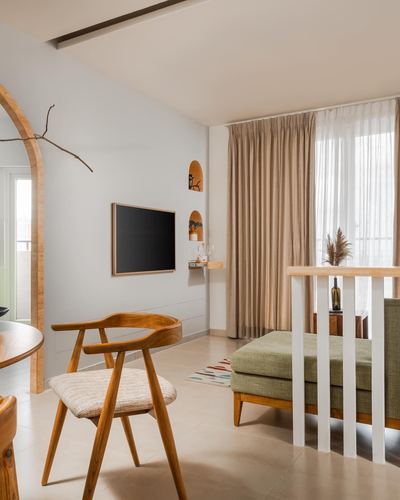 Minimalist living room with arched wooden doorway, niches, TV, and olive bench near curtained window