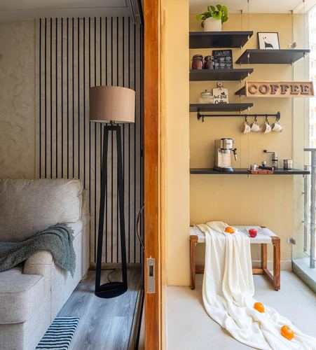 Living room with fluted wood wall and floor lamp opening to a yellow balcony coffee corner