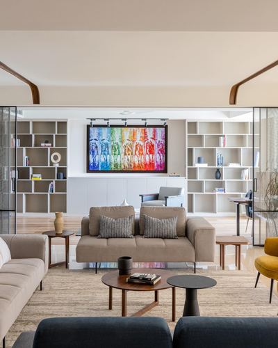 Neutral living room with symmetrical bookshelves and colorful framed artwork centered on the back wall