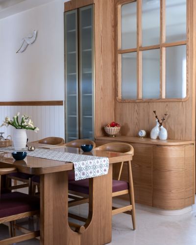 Wood-panelled dining room with oak table, maroon-cushioned chairs, and glass-fronted cabinetry