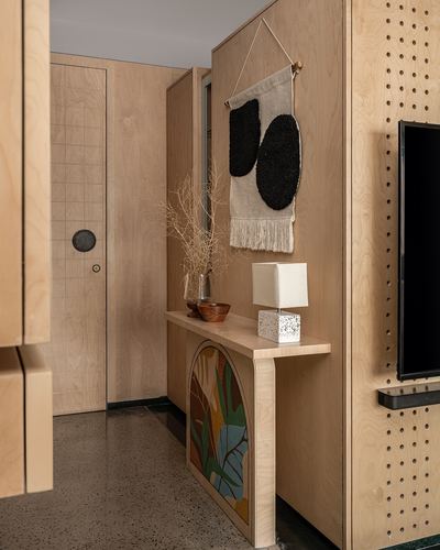 Plywood-clad foyer with console table, painted arch panel, and tufted wall hanging