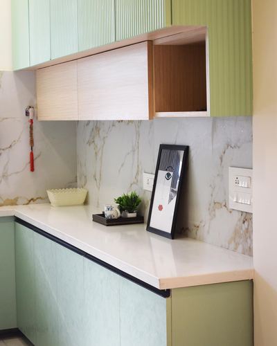 Kitchen corner with sage fluted cabinets, marble-look backsplash, and a wood-toned overhead shelf niche