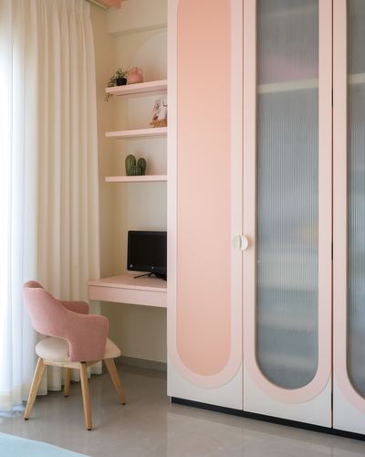Pastel pink study nook with fluted glass wardrobe, floating shelves, and upholstered chair