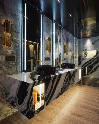 Long bathroom vanity in black and white marble with dual black vessel sinks and brass fittings