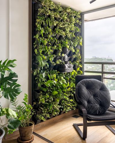 Balcony corner with vertical green wall, buddha statue, black chair and skyline view