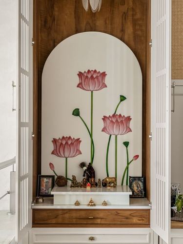 Arched pooja unit with hand-painted lotus mural, brass idols, and folding wooden doors