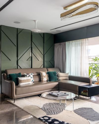 L-shaped taupe leather sofa against geometric green panelled wall with round marble coffee table