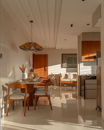 Sunlit open-plan dining area with rattan pendant light, wooden table and chairs, view into living room and kitchen