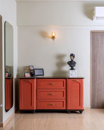 Terracotta Victorian-style dresser with brass handles, bust statue, and wall sconce in foyer