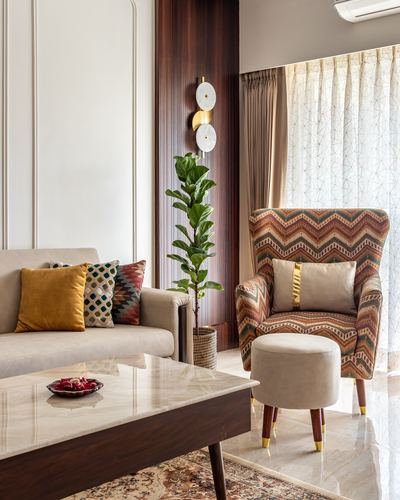 Living room corner with patterned wingback chair, marble coffee table, and fiddle leaf fig against wood panelling
