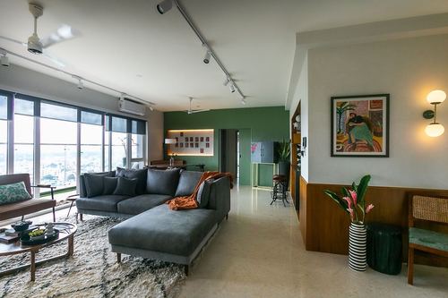 Living room with grey sectional, fluted green wall, city view through large windows