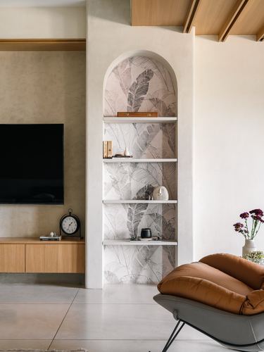 Arched niche with floral wallpaper and floating shelves beside a leather armchair in a living room