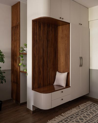 Rounded wardrobe unit with wood-panelled seating nook and ribbed doors in foyer