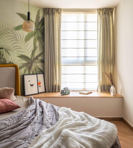 Bedroom window seat with tropical wallpaper, pendant light, and layered bedding in soft daylight