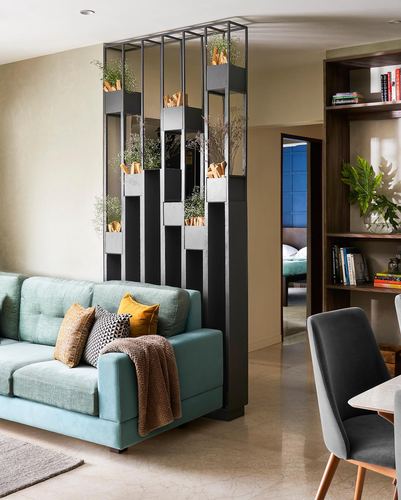 Teal sofa beside a black metal planter divider separating living room from hallway and dining area