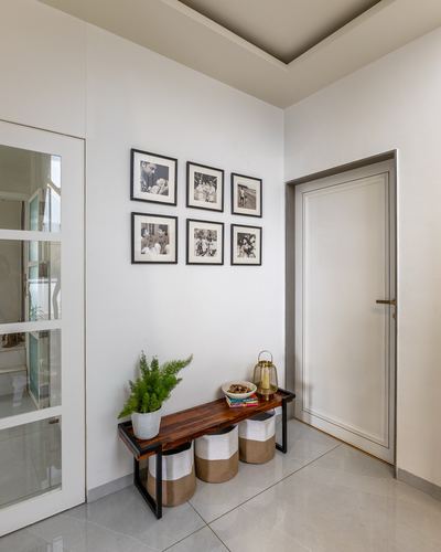 Foyer with black-and-white photo gallery wall above a wooden bench and baskets