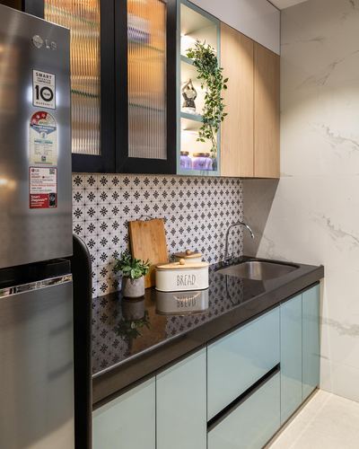Modern kitchen corner with pale blue cabinets, patterned tile backsplash, and wood-front upper cabinet