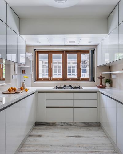White U-shaped kitchen with wooden-framed window above the gas hob and marble-look floor