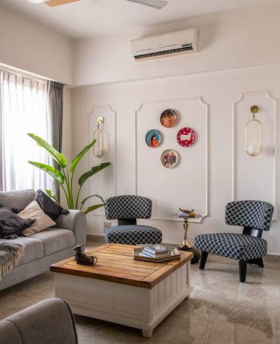Living room with paneled wall, hung plates, patterned accent chairs, and wood-topped coffee table