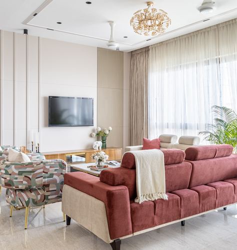 Living room with rose velvet reverse sofa, gold chandelier, and sheer curtained window
