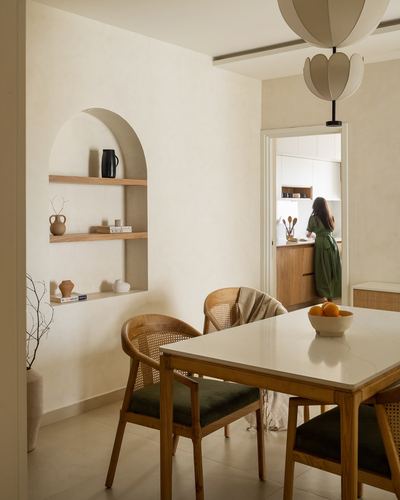 Dining room with arched shelf niche, cane chairs, stone table, and view into kitchen