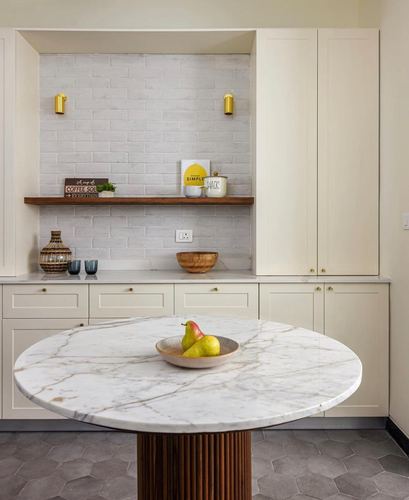 White kitchen with round marble table, fluted wood base, and tiled alcove shelf