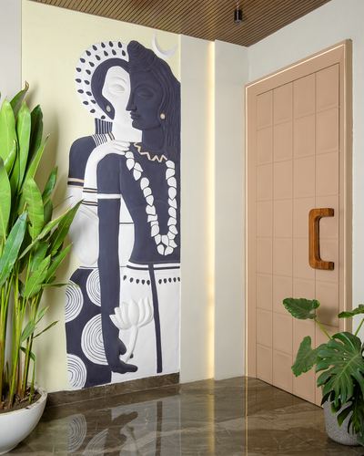 Entrance foyer with a carved Shiva-Parvati mural beside a blush panelled door and plants
