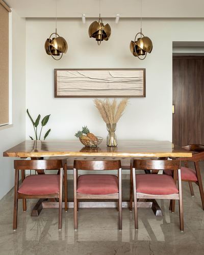 Dining room with live-edge wood table, dusty pink velvet chairs, and brass pendant lights