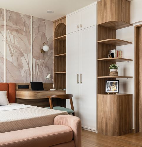 Bedroom corner with wood shelving, white wardrobe, study desk and leaf-print wallpaper