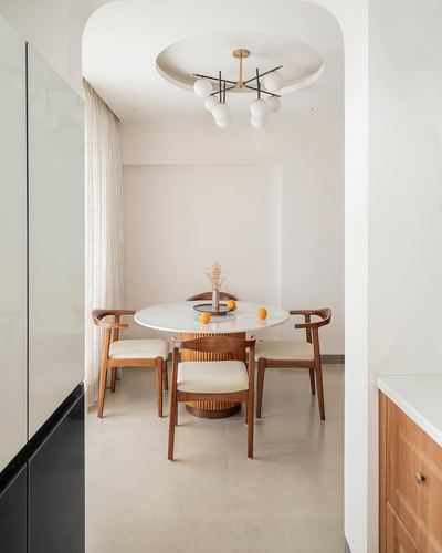 Round marble dining table with wishbone chairs seen through an arched doorway