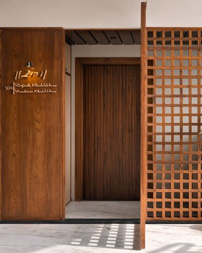 Entrance foyer with carved wooden lattice door beside a paneled teak door and marble floor