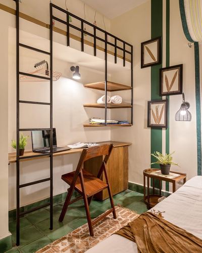 Corner study nook with black metal shelving, wooden desk, laptop, and green cement tile floor