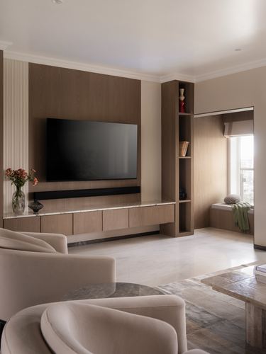 Living room with wood-panelled tv wall, marble floor, and window seat nook