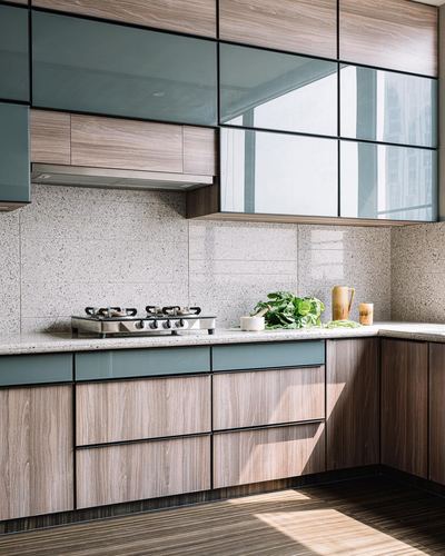 L-shaped modular kitchen with teal glass upper cabinets, wood lower cabinets, terrazzo backsplash