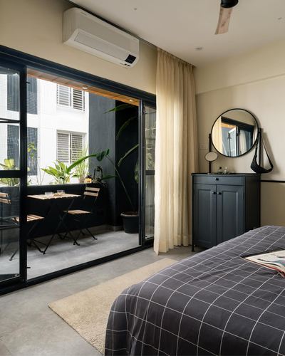 Bedroom with black cabinet, round mirror, and glass doors opening to a small balcony