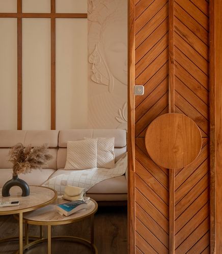 Living room corner with carved relief wall, beige sofa, and chevron wood sliding door
