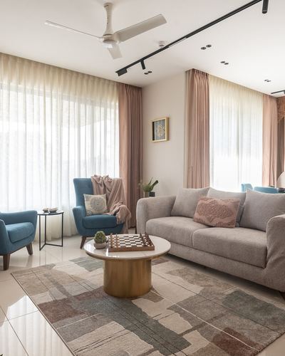 Living room with grey sofa, blue armchairs, and round marble coffee table under sheer curtains