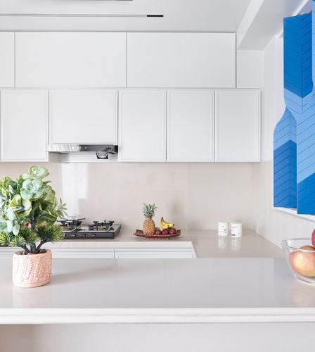 White modern kitchen counter with fruit bowl and blue geometric window feature