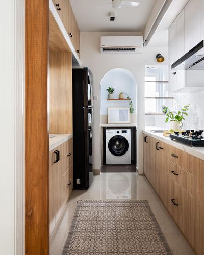 Galley kitchen in wood-toned cabinetry with an arched niche holding a washing machine and plants