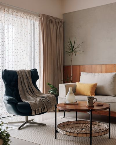 Living room corner with black leather swivel chair, wood coffee table with cane tray, and beige sofa